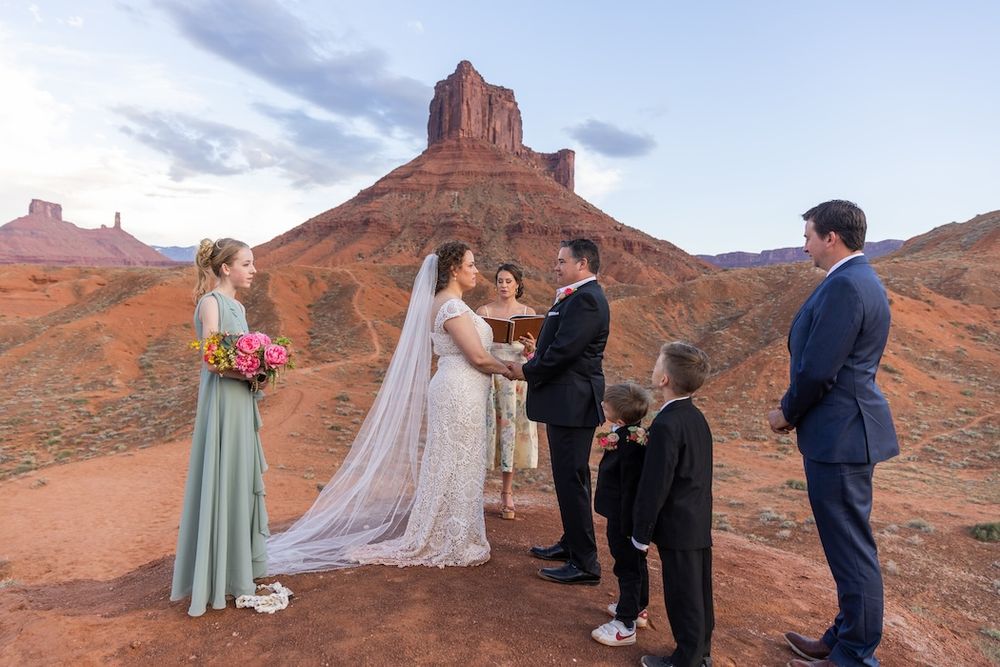 A wedding ceremony takes place in front of majestic red rock formations at Castle Valley, Utah.