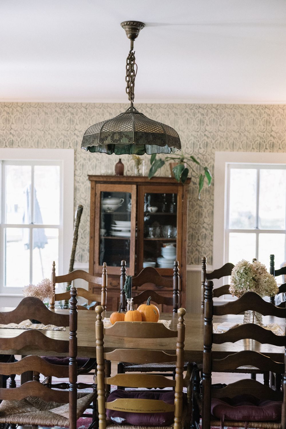 Traditional dining room with wooden chairs and china cabinets under vintage pendant lighting.