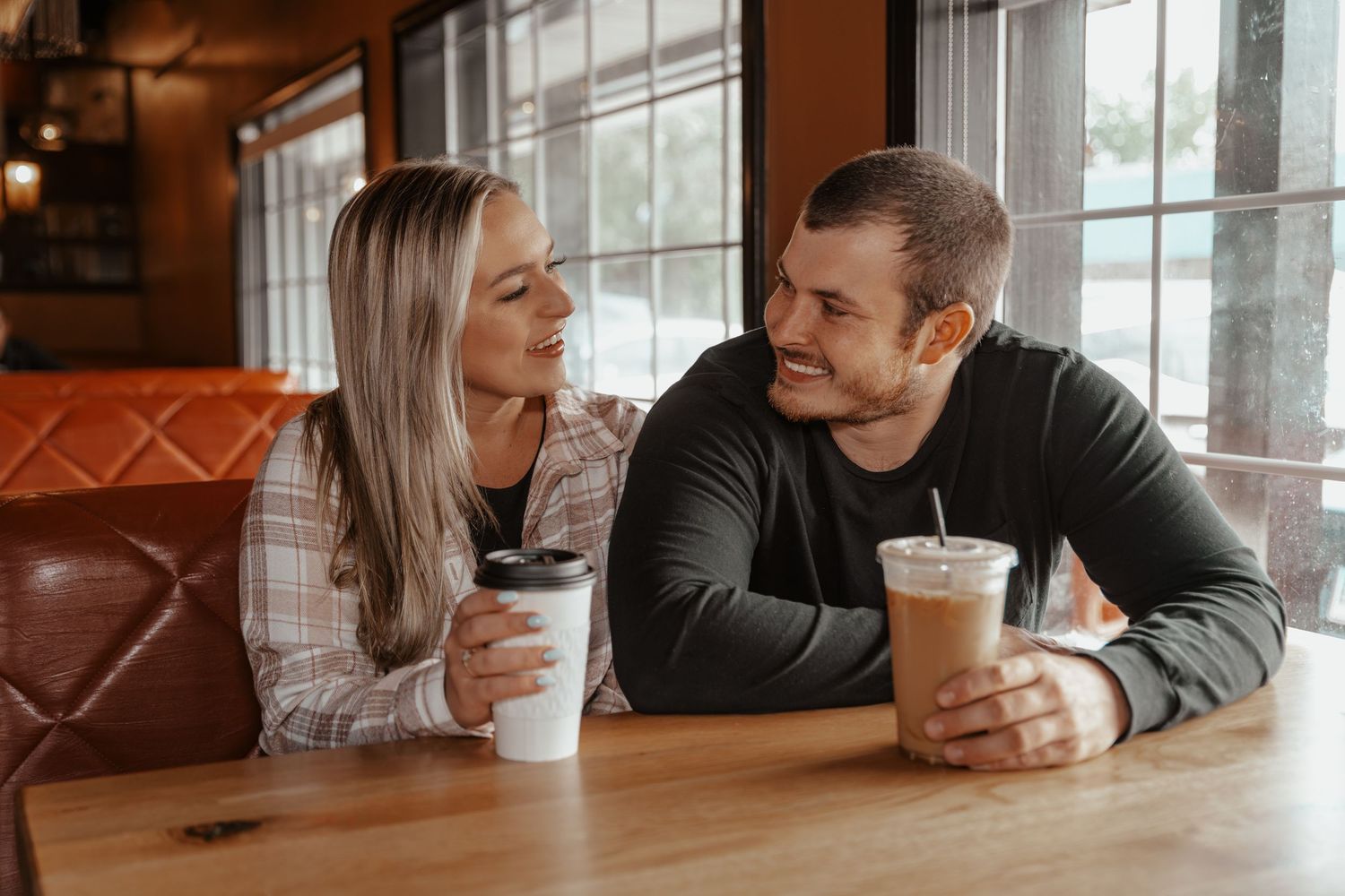 Happy couple sharing a warm moment at a coffee shop table with iced and hot drinks.