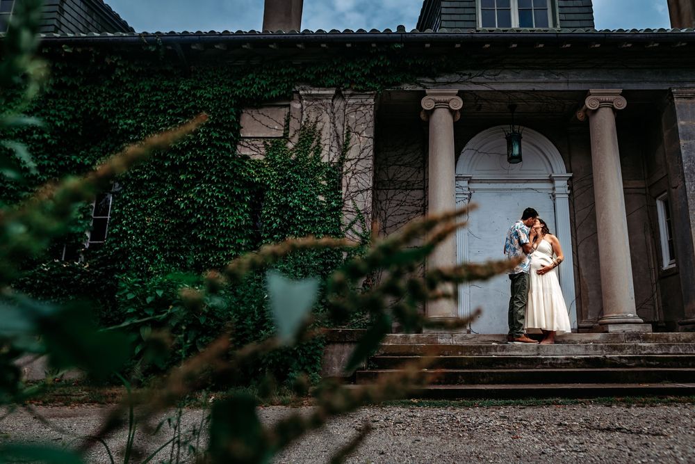 Elegant couple shares an intimate moment on a rustic porch surrounded by lush greenery and natural light.