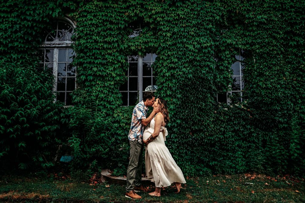 Couple embraces in front of an ivy-covered stone building during a romantic outdoor photo session.