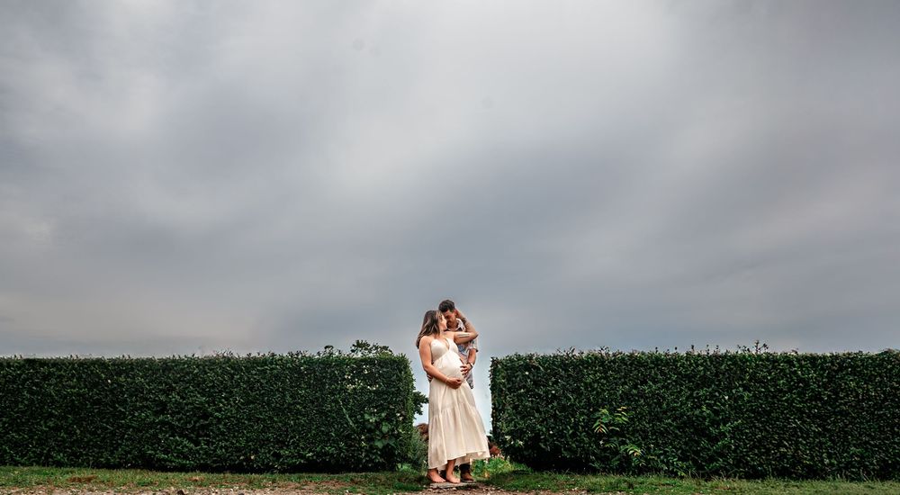 A couple shares a romantic moment on a scenic coastal cliff overlooking the ocean during an overcast day.