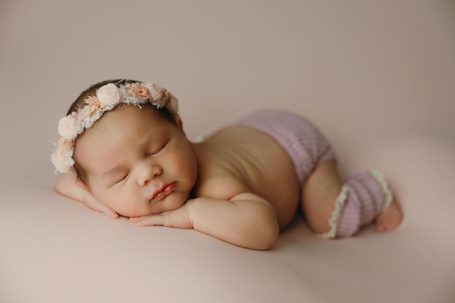 Sleeping newborn baby girl wearing a floral headband and knit bloomers posed at the newborn photo studio in victoria bc.