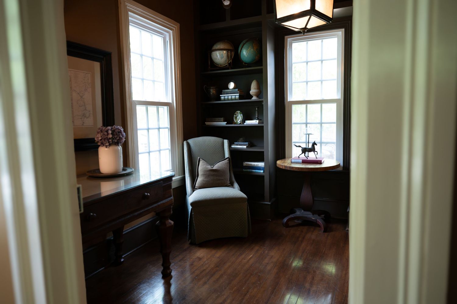 Interior panorama of an elegant room with dark wood floors and multiple windows.