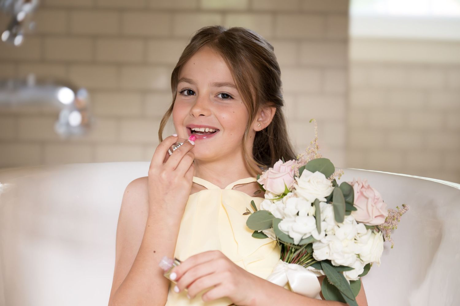 Person seated indoors holding white flowers while smiling joyfully.