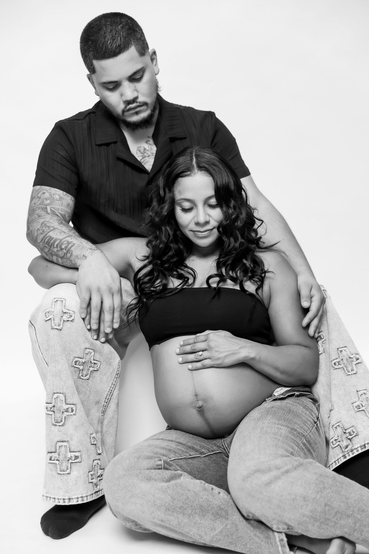 Maternity portrait of expectant mother in flowing pink tulle gown against neutral backdrop.