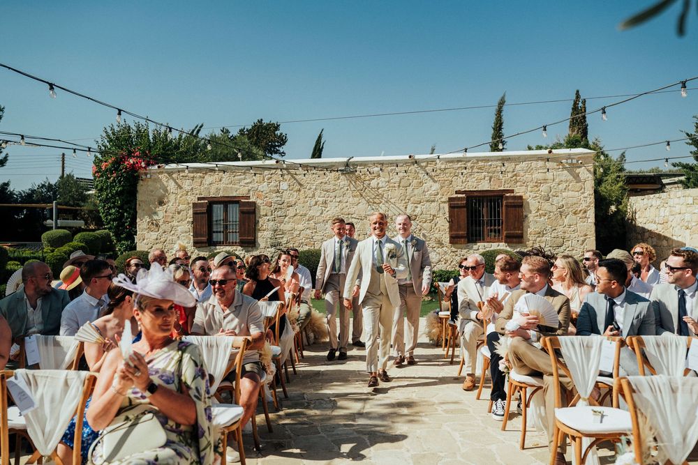String lights illuminate an outdoor wedding reception venue with rustic stone walls and white table settings.