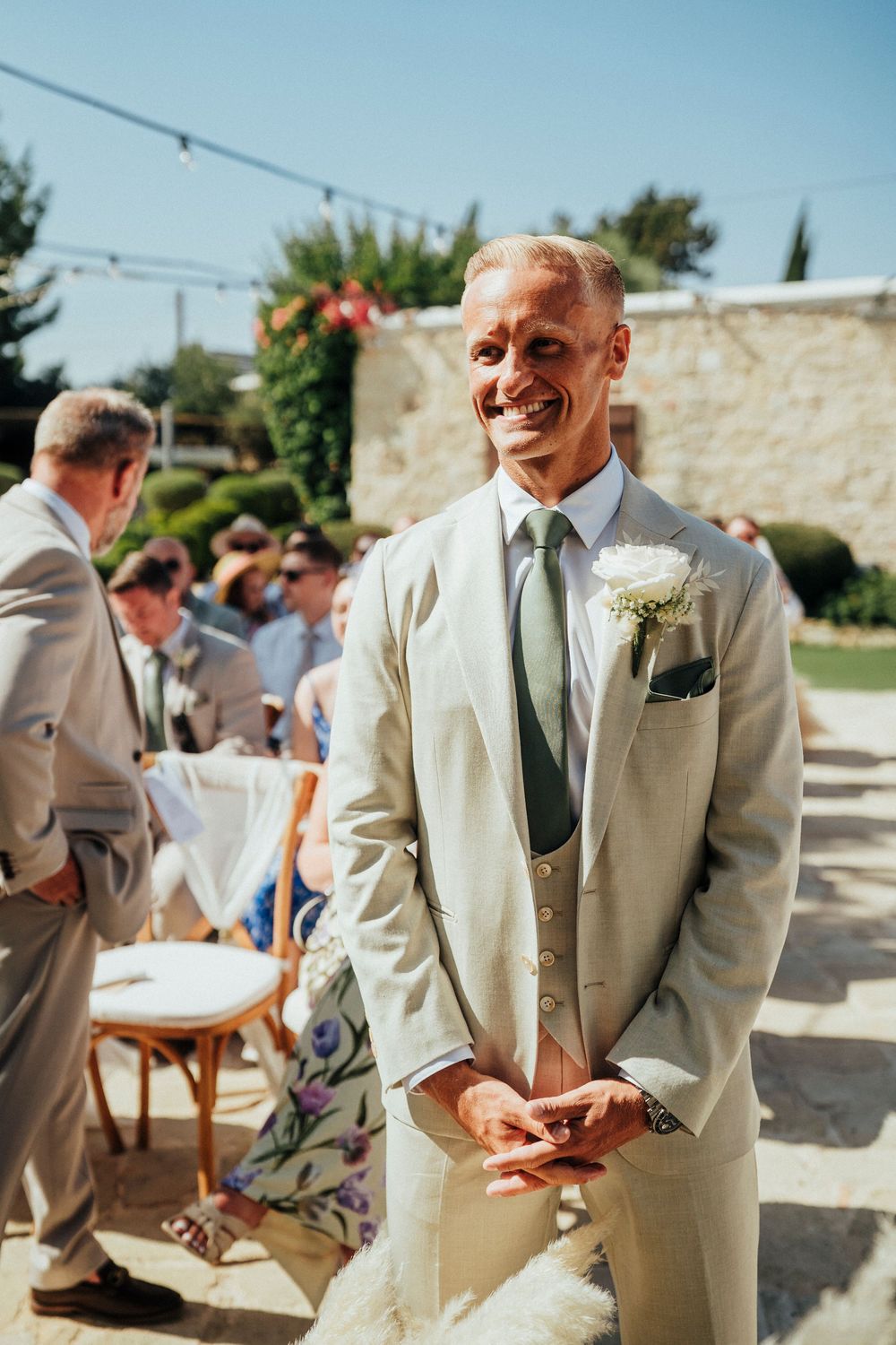 A series of candid moments showing guests in light-colored suits at an outdoor wedding reception on a sunny day.