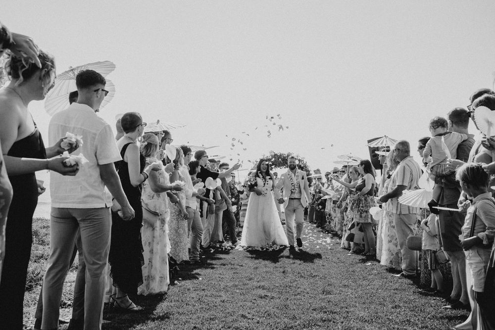 A large crowd of spectators stands in a line watching an event in a black and white photograph.