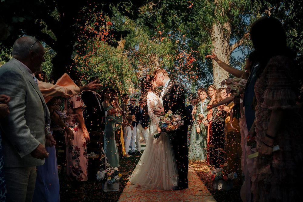Wedding guests celebrate and dance together under twinkling lights at an outdoor evening reception.