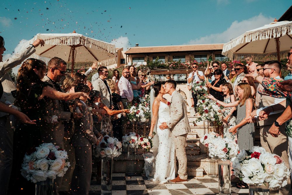 Wedding guests dance and celebrate at an outdoor reception venue during sunset.