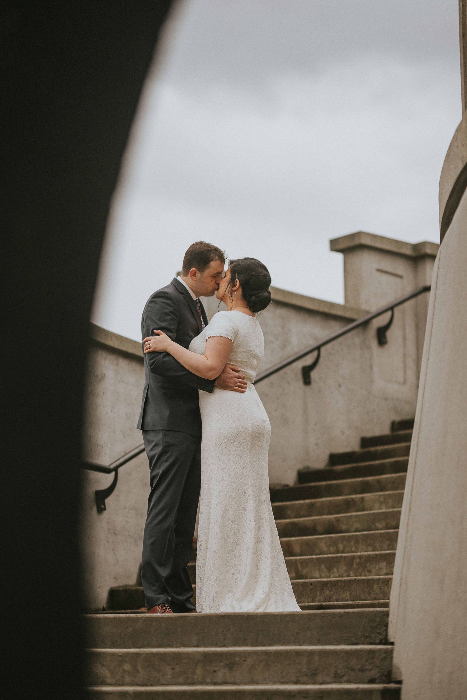 Romantic wedding couple embraces on stone steps during an intimate outdoor moment.