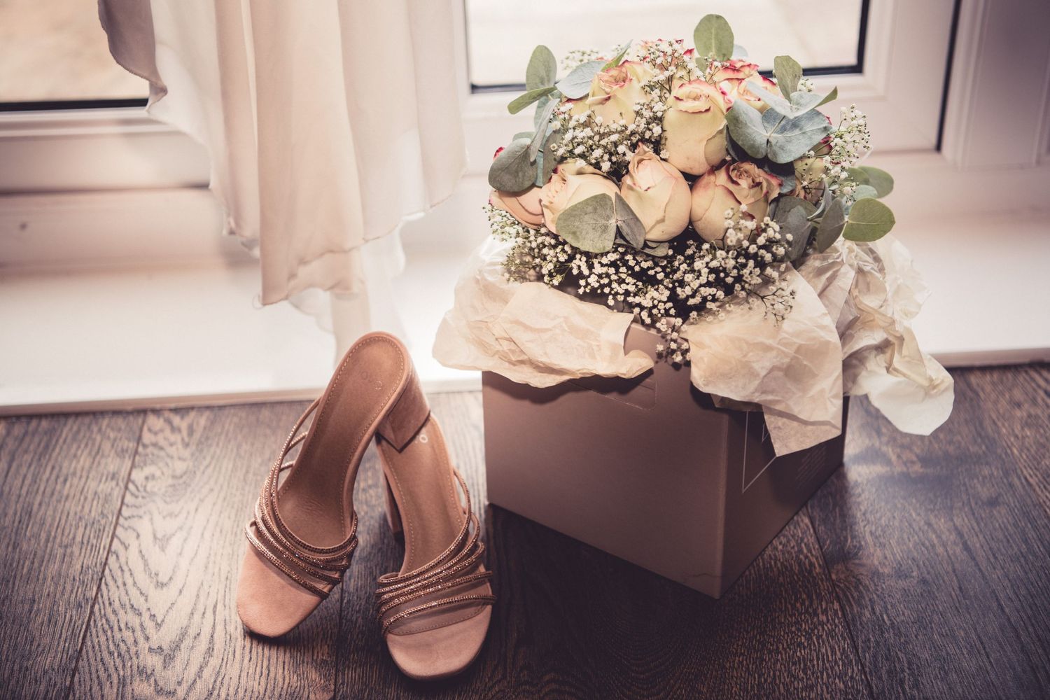 Wedding bouquet with white flowers and eucalyptus leaves arranged on wooden floor.