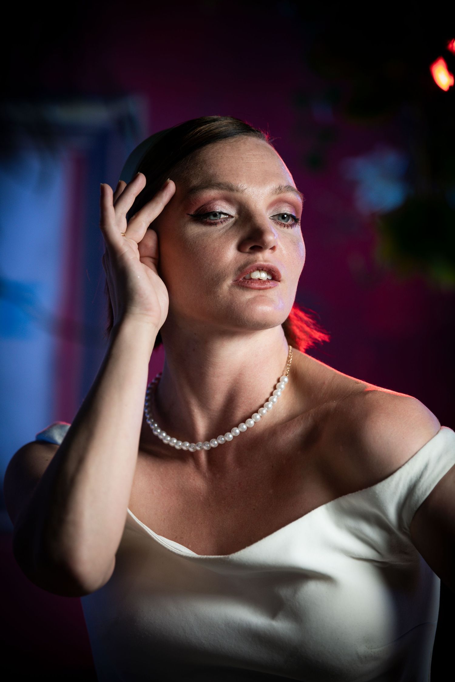 Dramatic portrait series featuring an elegant white evening gown and pearl necklace against dark backdrop.