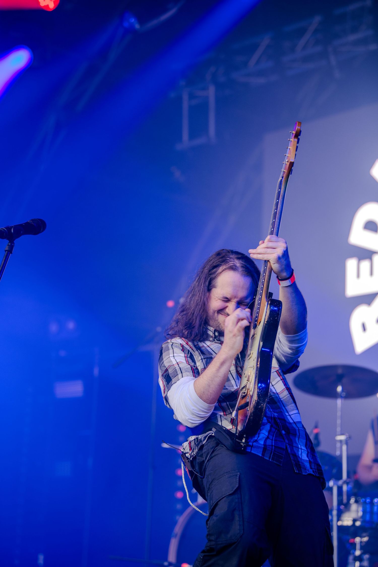 Concert performer singing passionately under dramatic blue stage lighting during live music performance.