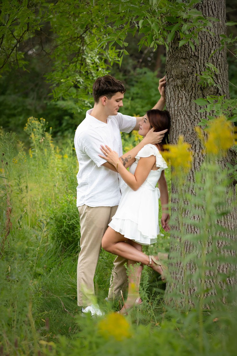 sweet moment between man and woman leaning on a tree