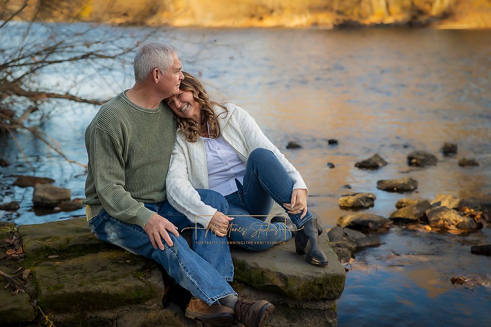 Engaged older couple sitting together laughing near river