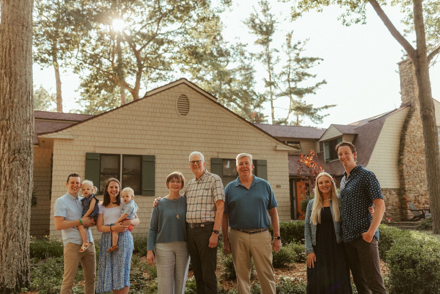 Large family group gathered outside suburban home during golden hour.