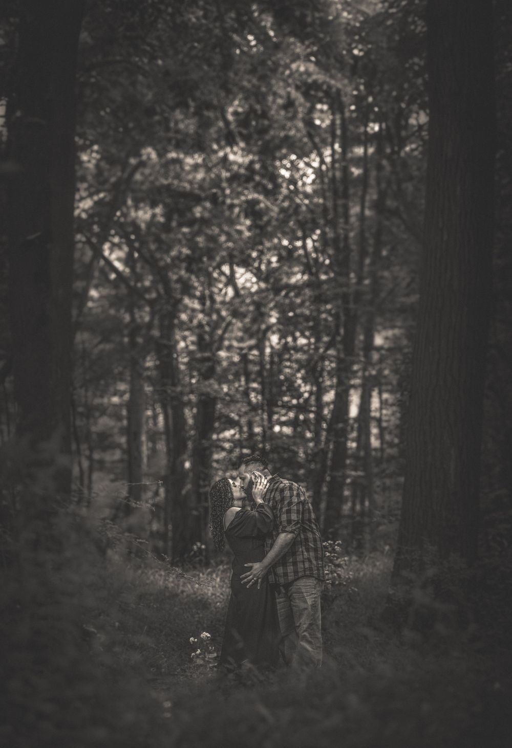 A ghostly silhouette stands in a dark misty forest, creating an eerie atmospheric black and white scene.