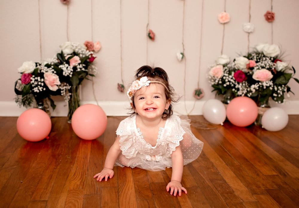 Baby girls first birthday session with balloons and flower garland