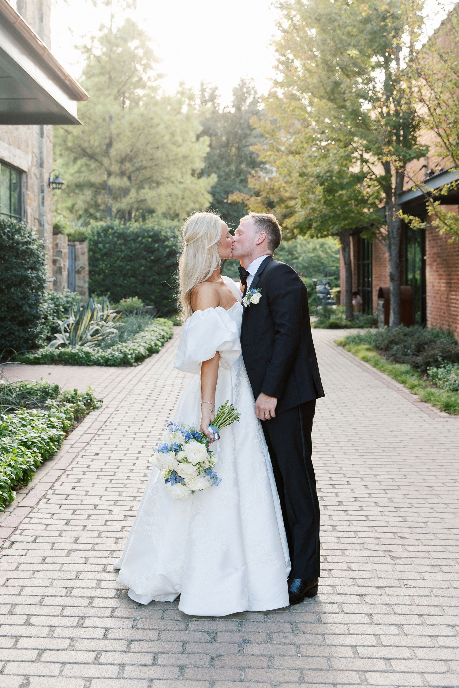 Romantic wedding photo sequence on stone pathway surrounded by lush gardens.