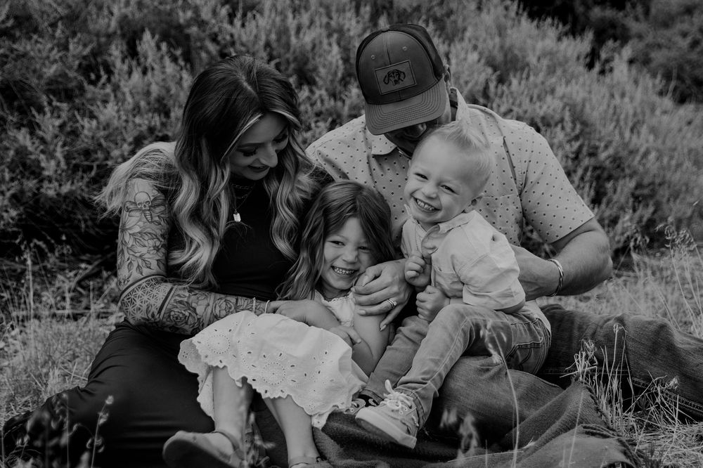A black and white photo sequence showing a family playing and laughing together outdoors in nature.