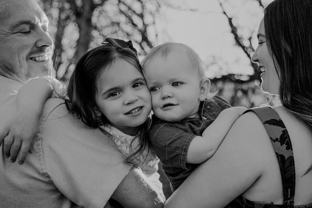 A joyful black and white collage of candid family moments showing laughter and embraces.