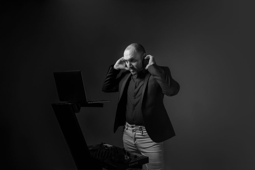 Professional musician in dark studio working with laptop in dramatic lighting.
