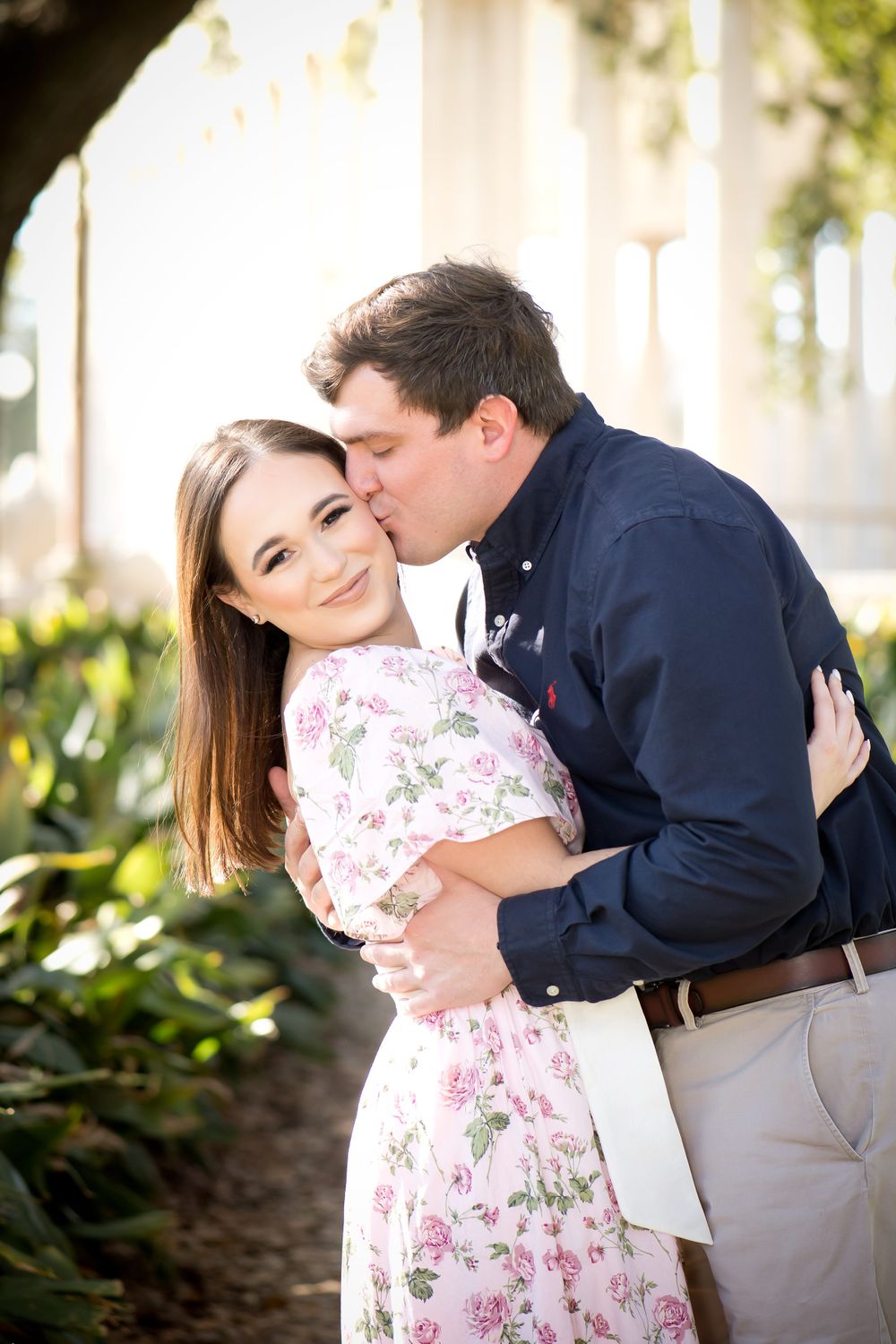 Couple shares intimate moments in a floral dress and navy shirt among white columns.