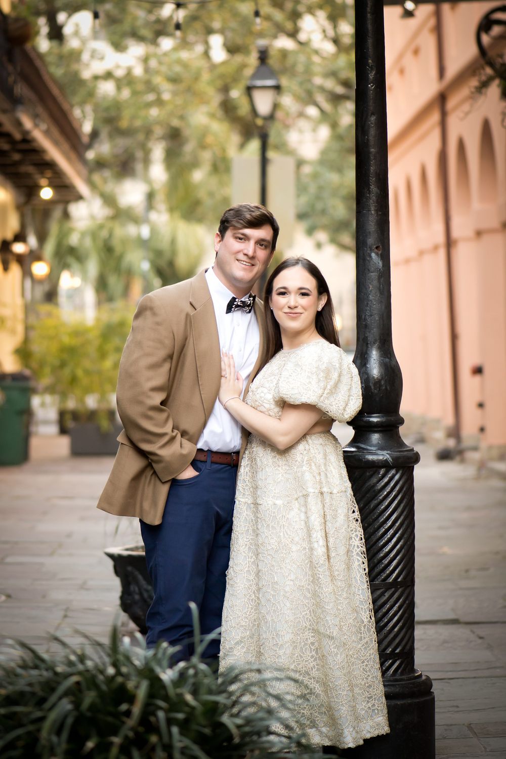 Romantic photoshoot along a historic street with ornate lamp posts and architecture.