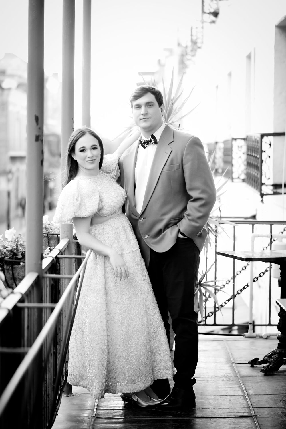Black and white portraits captured along a historic covered walkway with iron railings.