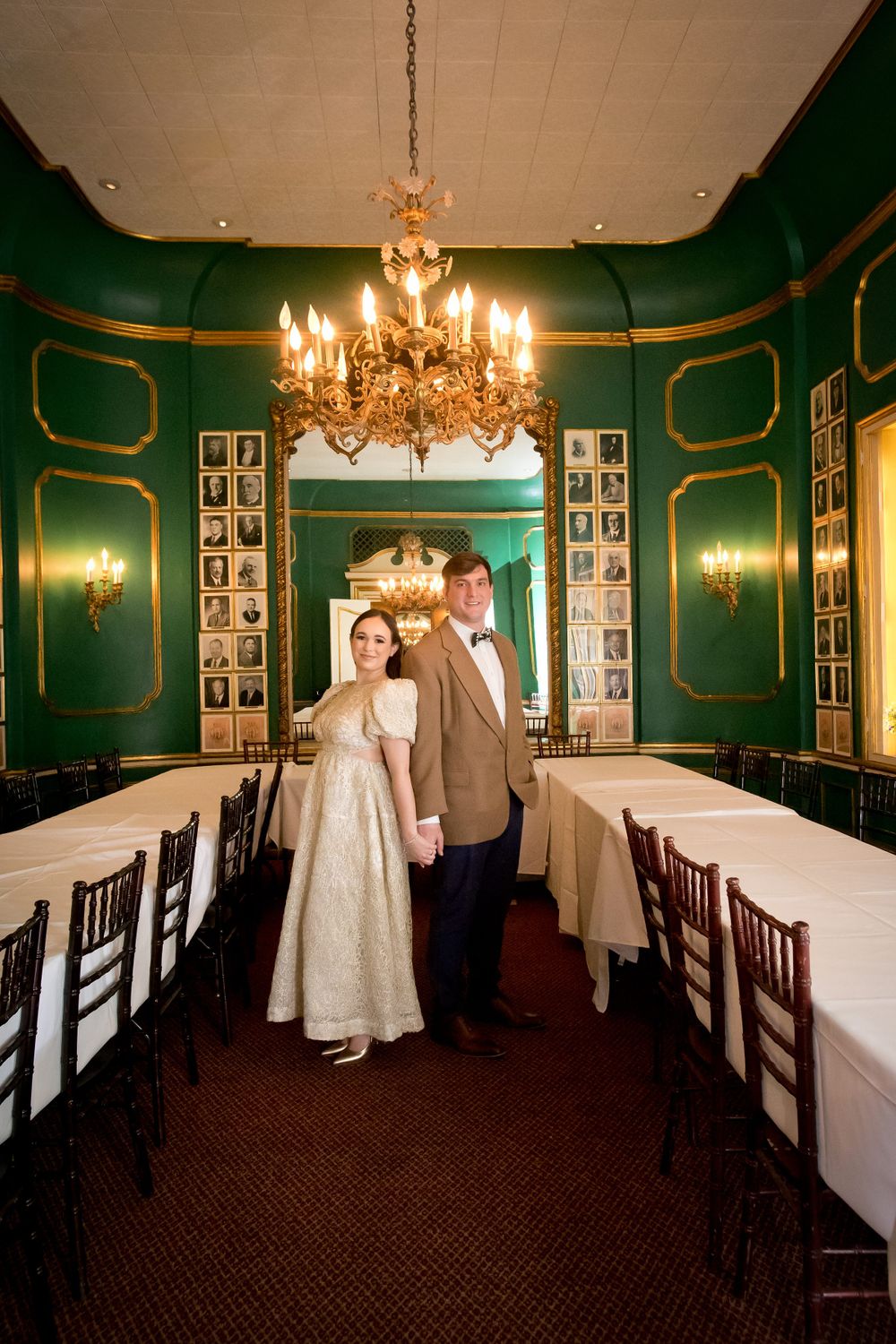 Elegant dining room with green walls, chandeliers and white tablecloths at Antoine's Restaurant.