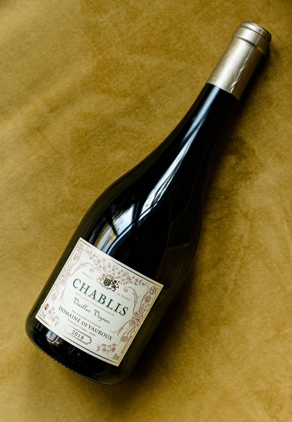 Chablis wine bottle photographed on brown textured background.