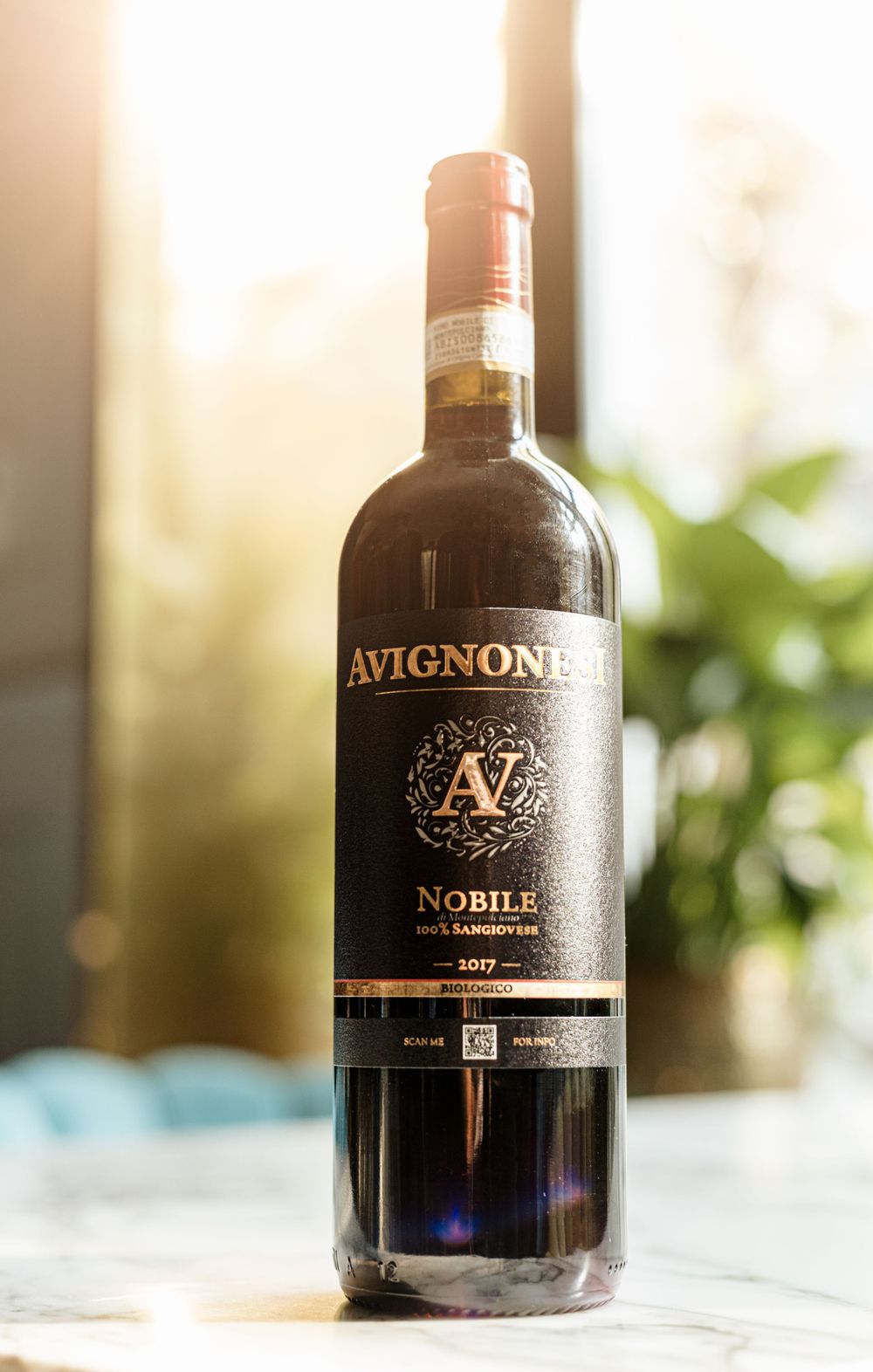 Avignone Nobile red wine bottle backlit against window with natural light.