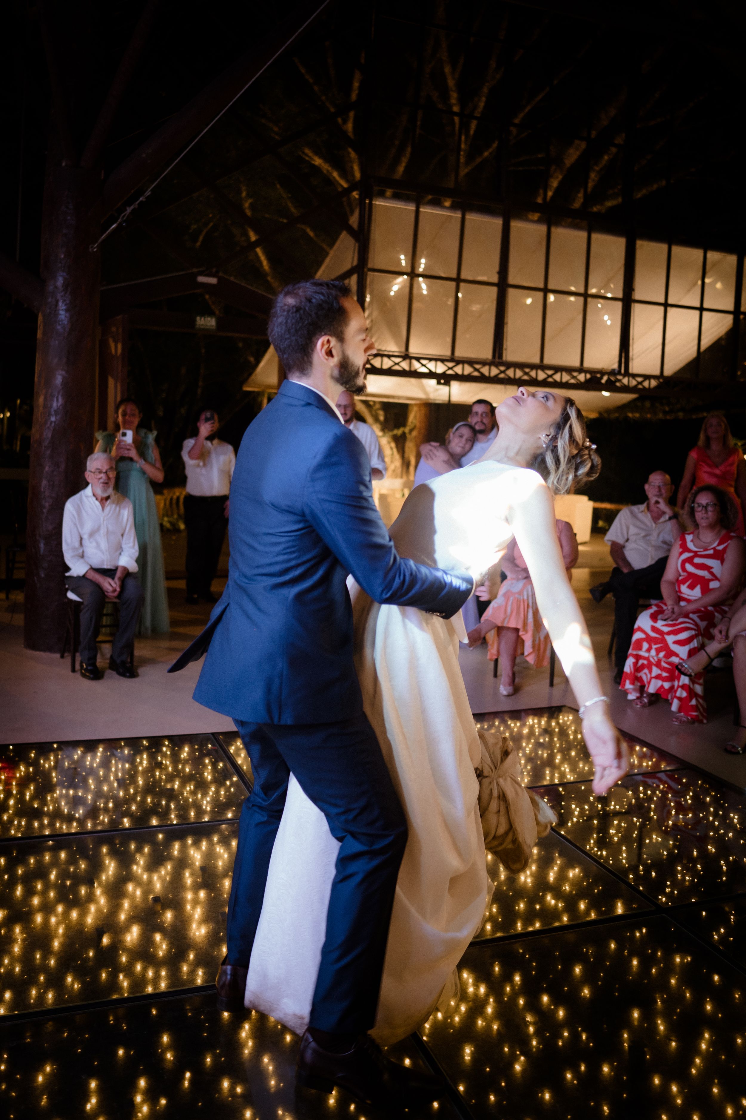 A celebratory dance scene with fairy lights glowing beneath the dancers on an outdoor stage.