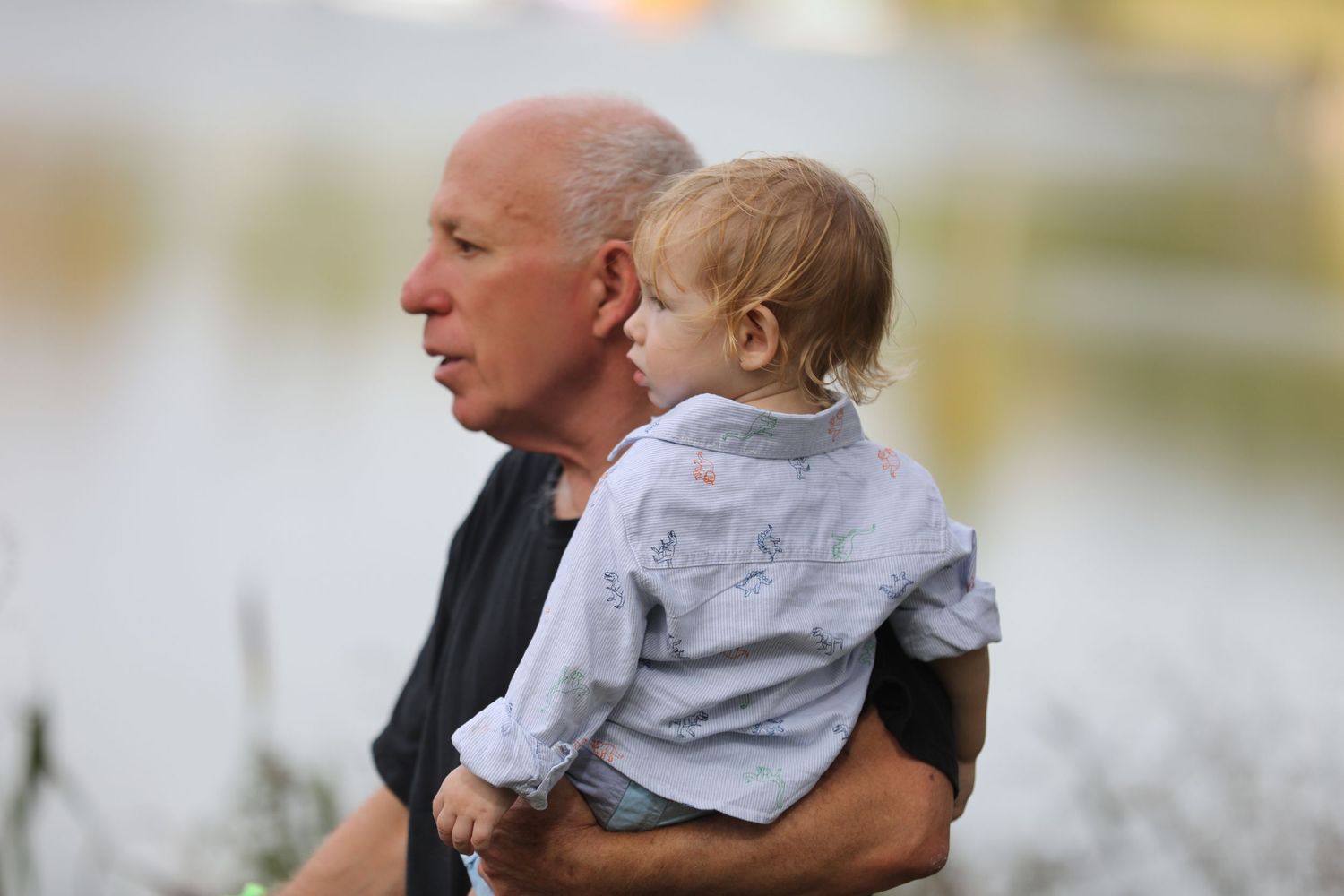 A tender moment between an adult and toddler looking out at a waterfront view.