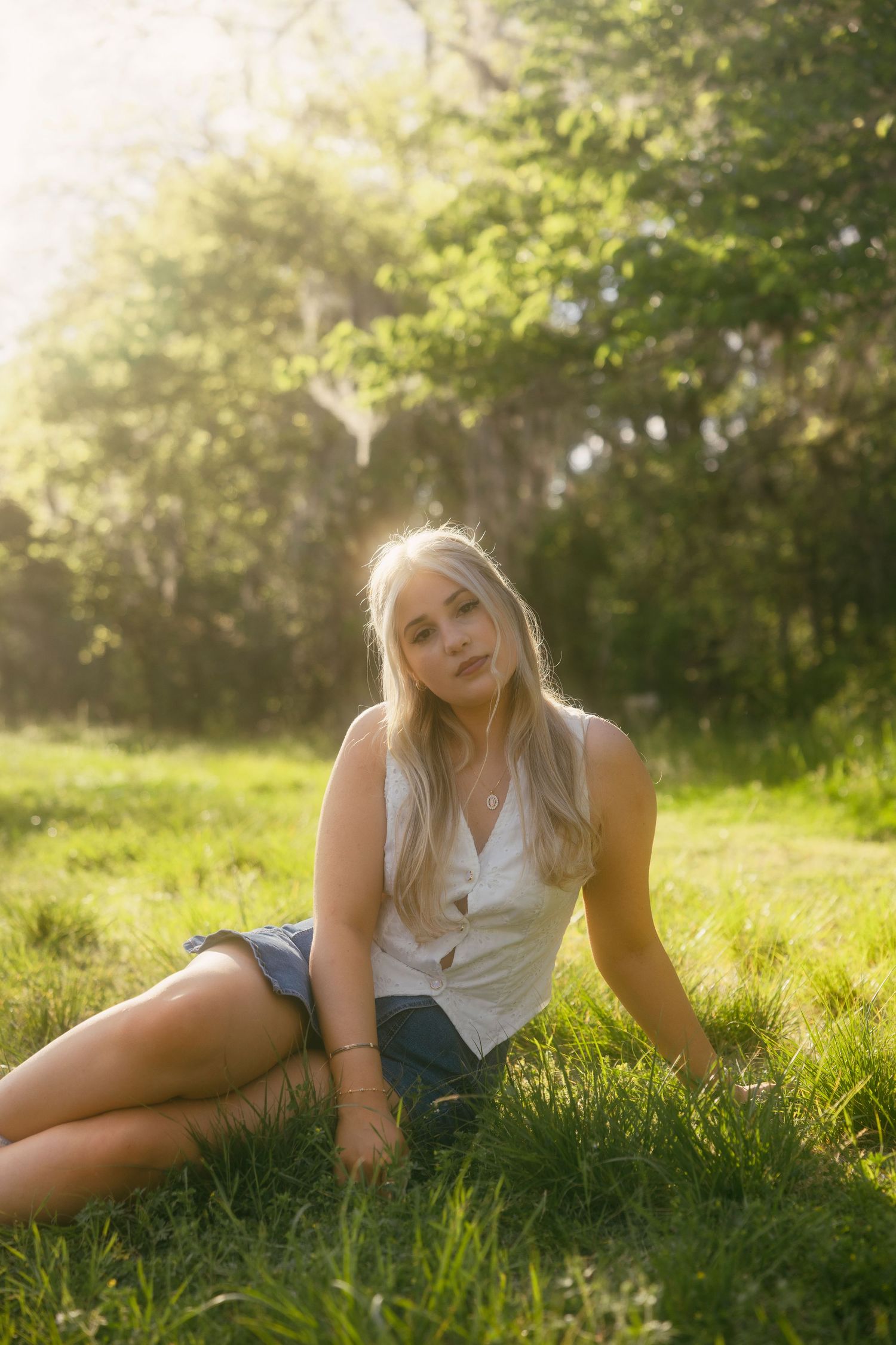 Person in black crop top and jeans poses against autumn landscape with golden foliage and white birch trees.
