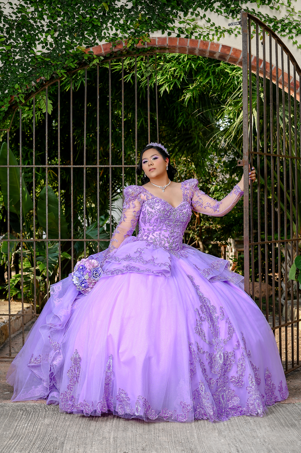 Lavender quinceanera dress with intricate beading photographed under garden archway.