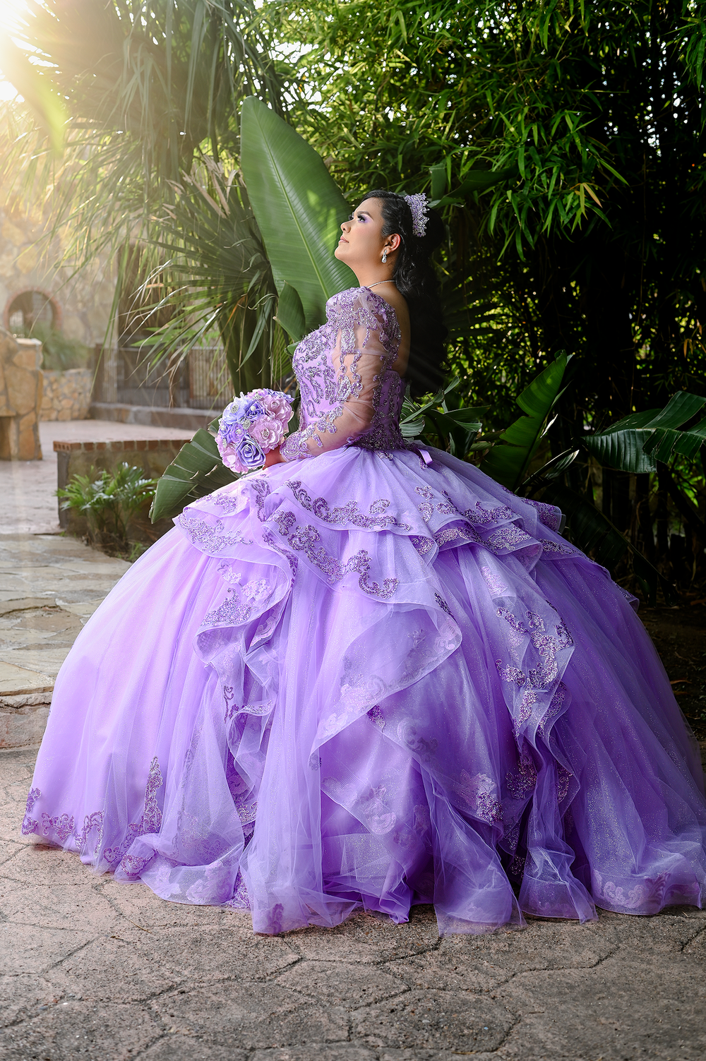 Lavender quinceanera dress with full skirt captured in tropical garden setting.