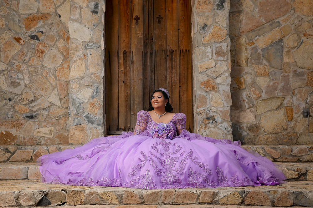 Purple ballgown dress photographed against rustic stone doorway and steps.