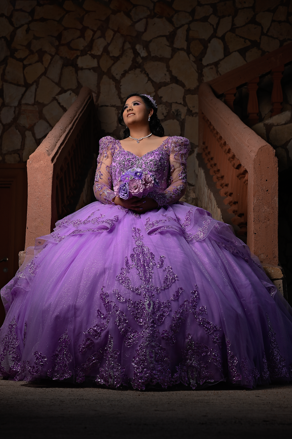 Elegant purple ball gown with intricate beading photographed against stone stairs.