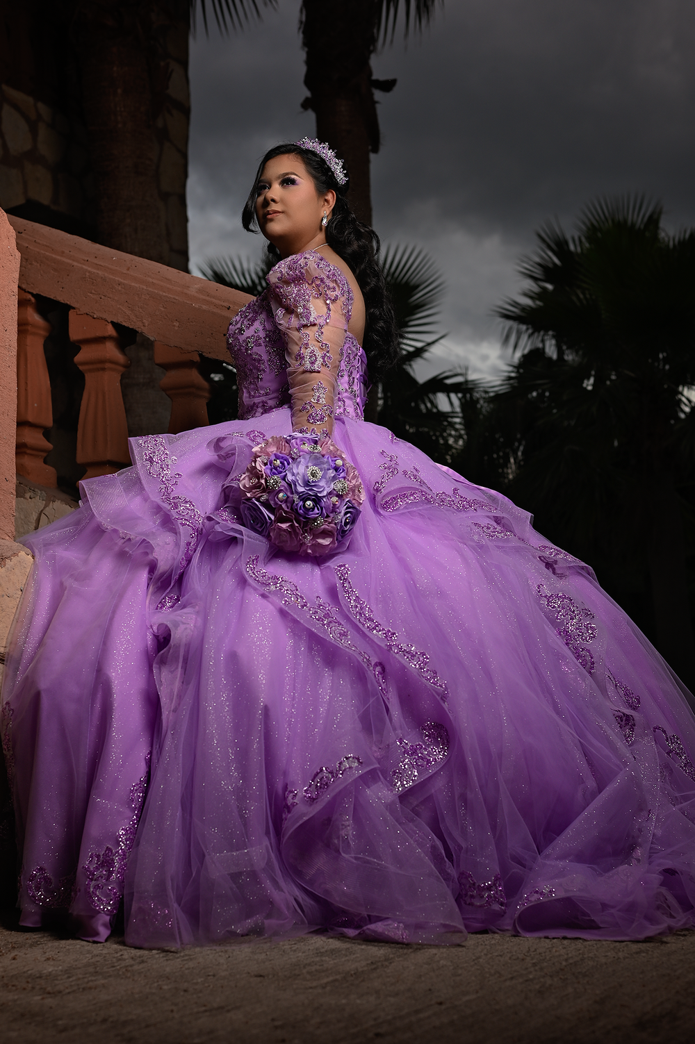 Moody outdoor portrait featuring a lavender ball gown against palm trees at dusk.