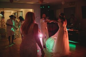 Wedding celebration on dance floor with atmospheric lighting and flowing dresses.