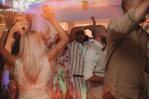 Wedding reception guests dancing enthusiastically under colorful party lights.