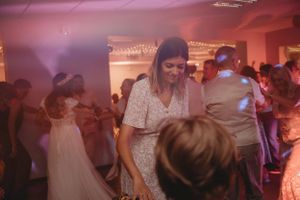 Wedding reception guests dancing and celebrating in a festively lit indoor venue.