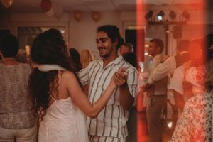 Couples dancing together at a lively wedding reception with warm lighting.