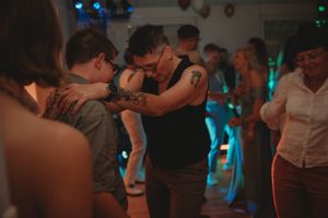 Close group of people dancing together in dimly lit room with blue lighting accents.
