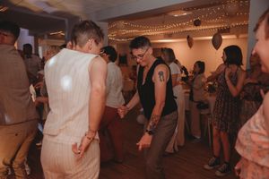 Party guests dancing and enjoying themselves under string lights at indoor celebration.