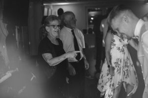 Black and white photo of guests dancing at a lively wedding reception.