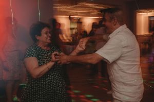 Guests dancing together under colorful disco lights at a wedding reception.